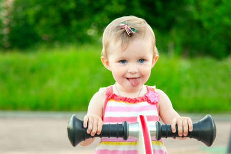 little funny baby girl smiling and swinging on swing on playground. happy kid outdoors at park summer. Copyspaceの写真素材