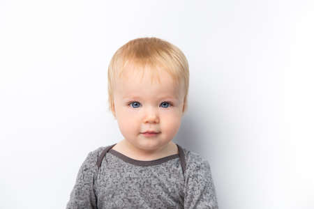 Infant child baby boy in gray shirt laughs happy looking at the camera isolated on a white...