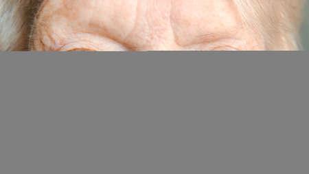 Sad blue gray eyes of an elderly woman looking at camera, extreme close up shot. vision and concept of older people bannerの写真素材