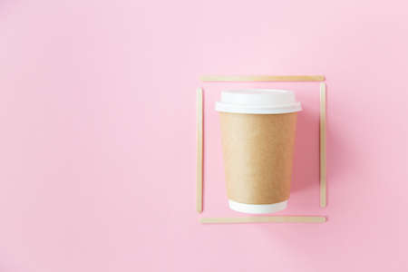 eco disposable glass with a plastic lid for coffee with a frame of wooden sticks on a pink background. ecologyの写真素材