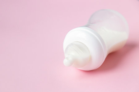 Baby milk bottle on a pink background with neagtive space.の写真素材