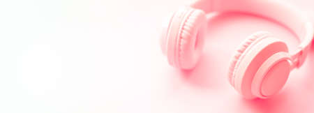 pink headphones on pink background. Minimalist simple photo of earphones with copy space, Closeup banner. Music and New technologies concept. Trendy minimal music deviceの写真素材