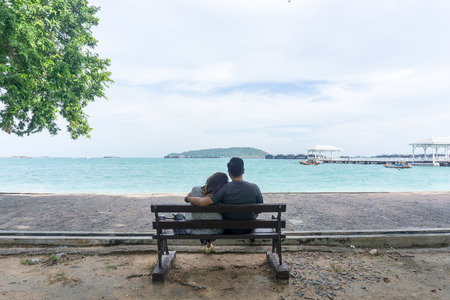 back view of couple sitting on the bench looking to the seascape  with sea and sky background. love couple or family or valentine day concept.の写真素材