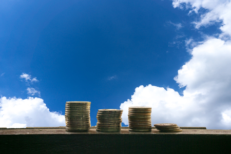 stack of coin in different position with blue sky with cloud background. money finance concept. money is god. money on the sky. money in our dreamの写真素材