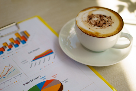 soft tone image of business document with latte art coffee on the wooden table and windows light during coffee break of meeting. business and coffee conceptの写真素材