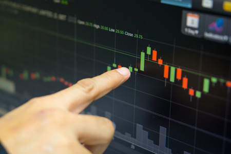 business man or broker point finger at green candle stick that stock prices skyrocket with indicator...
