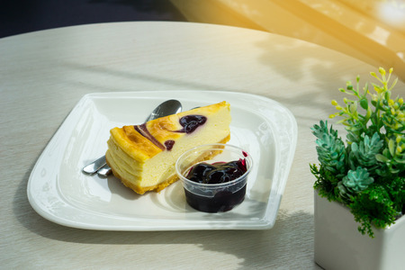 pieces of cake with blueberry jam near small tree on the table with blurred background.の写真素材
