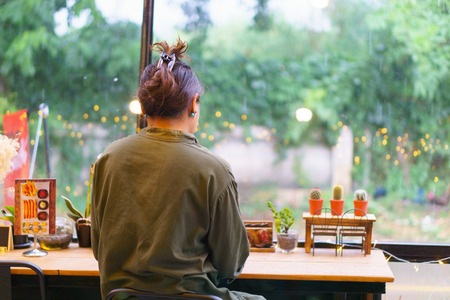 young beautiful asian female drinking espresso coffee at the old vintage bar table near long modern windows glass in cafeの写真素材