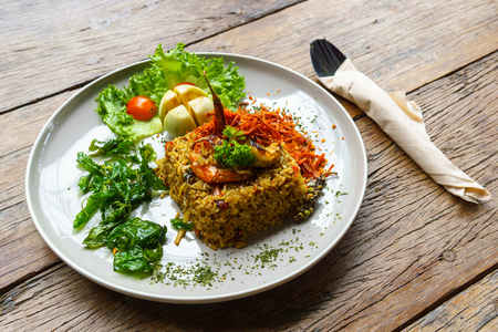 Spicy Fried rice with crispy pork skin with cutlery on wooden table.  thai fusion food.の写真素材