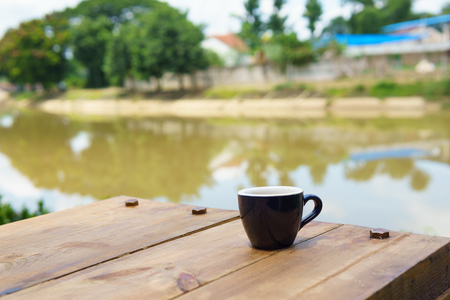 espresso or ristretto coffee in dark blue cup on the wooden table near the river in sunny day.の写真素材
