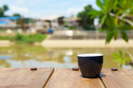 espresso or ristretto coffee in dark blue cup on the wooden table near the river in sunny day.の写真素材