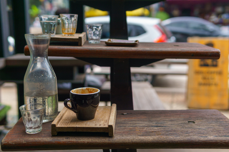close up of empty espresso coffee in dark blue cup with water in transparent glass in the wooden plate on the stairs.の写真素材