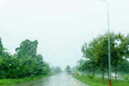 blurred beautiful drop of rain on glass or windows surface with road background. blurred dew or raindrop on glass surface for abstract backgrounの写真素材