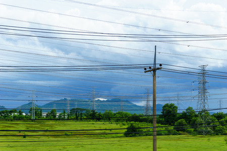 low voltage pole with high voltage electricity pylon and transmission line background in the filed...