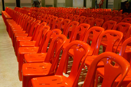 Row of well organized red plastic chair in the plearnary hall for biggest event.の写真素材