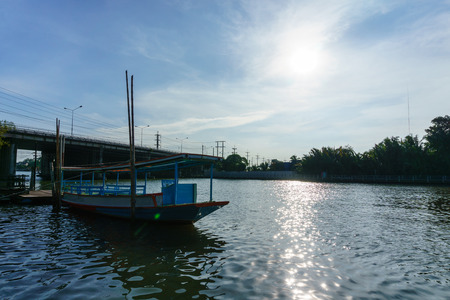 beautiful landscape view of mae klong river,samutsongkram,thailand with bridge and blue sky and cloud against sun while the passenger boat is floating or parking in the evening.の写真素材