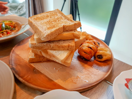 close up, pile of grilled bread with other food on the wooden dish in the morning for breakfast.