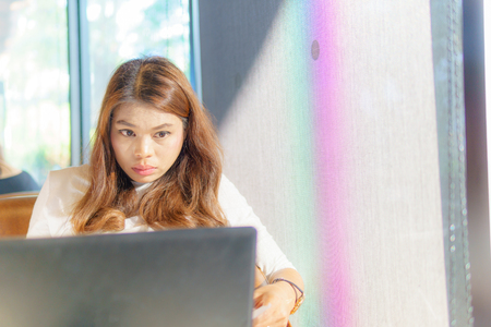 beautiful asian young business woman sit near transparent window and look at  laptop for her job at cafe or coffee shop. business success concept.の写真素材