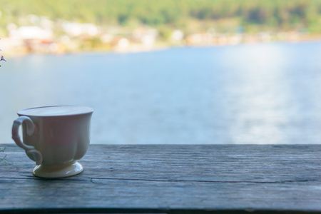 close up view of latte art coffee in white ceramic glass on the wooden plate with pond background.の写真素材