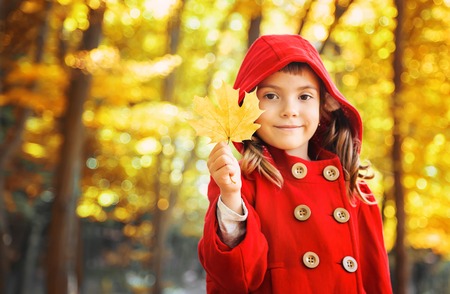 child in a red coat with autumn leaves. Love autumn. Selective focus. nature.の写真素材