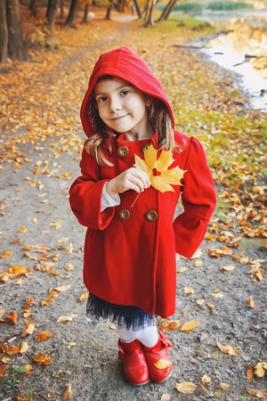 child in a red coat with autumn leaves. Love autumn. Selective focus. nature.の写真素材