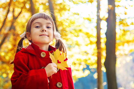 child in a red coat with autumn leaves. Love autumn. Selective focus. nature.の写真素材