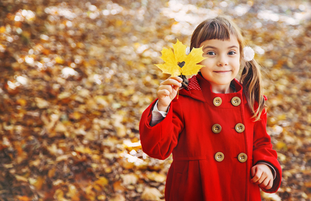 child in a red coat with autumn leaves. Love autumn. Selective focus. nature.の写真素材