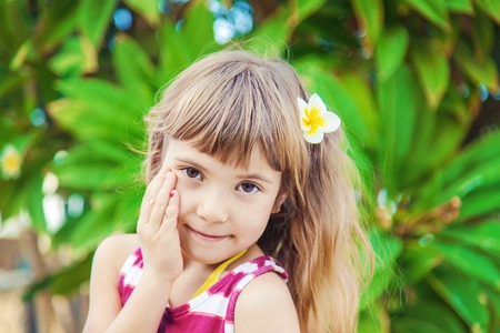 girl with a plumeria flower in her hair against the backdrop of palm trees. Selective focus. nature.の写真素材