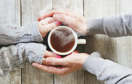 A cup of tea in the hands of a man and a woman. Selective focus. cute.の写真素材