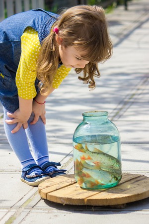 A child is playing with fish in a can. Selective focus.の写真素材