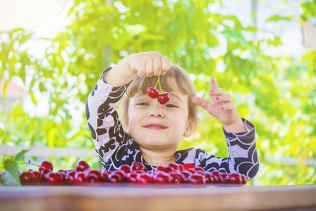 The child is picking cherries in the garden. Selective focus.の写真素材