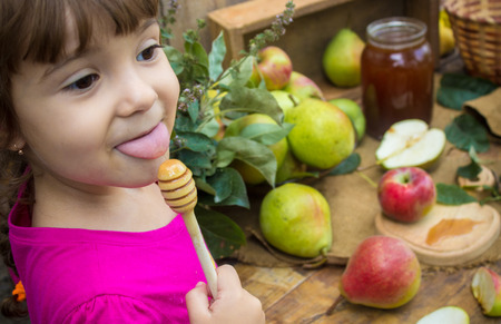 The child eats honey and apples. Selective focus.の写真素材