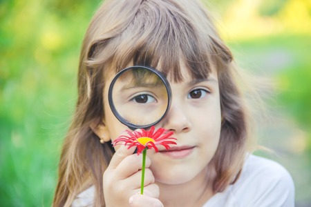 The child is looking in a magnifying glass. Increase. selective focus.の写真素材