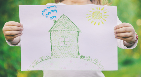 Drawing of a green house in the hands of a child. nature.lの写真素材