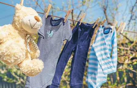 Baby clothes and accessories weigh on the rope after washing in the open air. Selective focus. nature.の写真素材