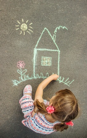 The child draws the house with chalk on the asphalt. Selective focus. draw.の写真素材