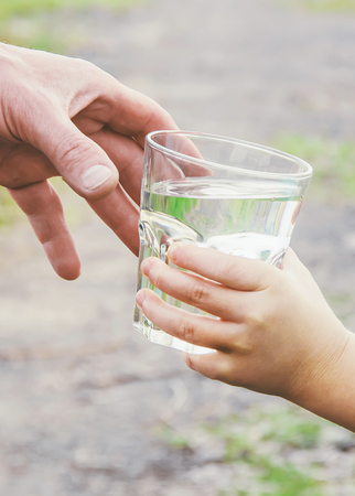 The father gives the child a glass of water. Selective focus. drink.の写真素材