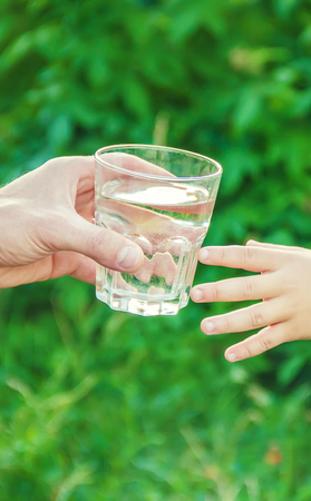 The father gives the child a glass of water. Selective focus. nature.の写真素材