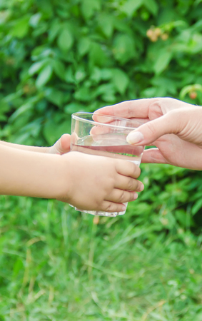 The father gives the child a glass of water. Selective focus. nature.の写真素材