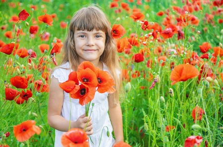 children girl in a field with poppies. selective focus.の写真素材