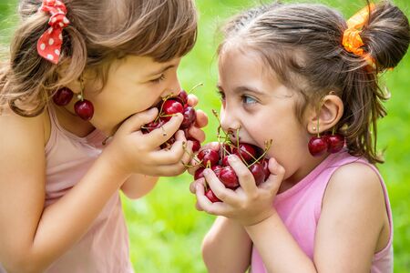 Children eat cherries in the summer. Selective focus.の写真素材