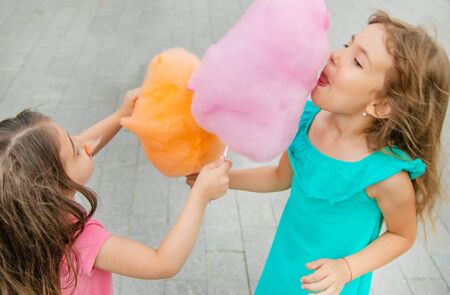Children eat cotton candy in the park. Selective focus.の写真素材