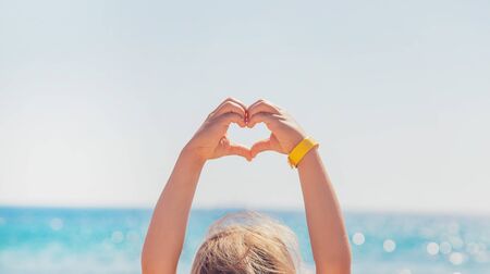 child makes hands heart on the background of the sea. Selective focus. nature.の写真素材