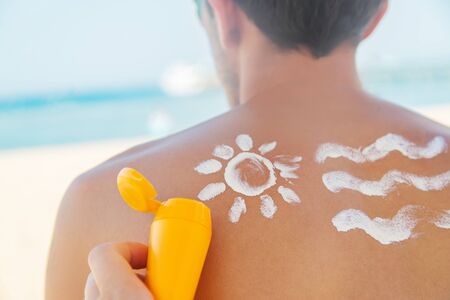 The girl on the beach applies sunscreen to the skin of a man. Selective focus. nature.