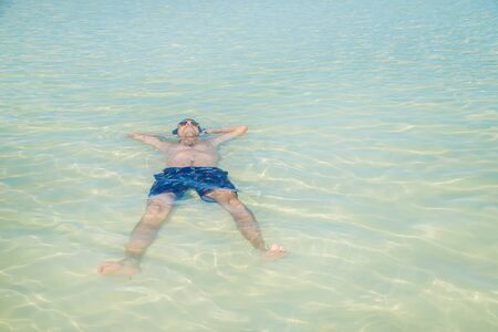 A man swims in the sea lying on his back. Selective focus.
