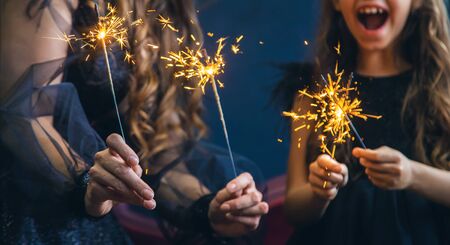 Mother and daughter lit sparklers on Christmas night. Selective focus. Holiday.の写真素材