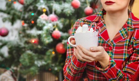 Christmas morning, girl in pajamas with a cup of hot cocoa with marshmallows. Selective focus. Holiday.の写真素材