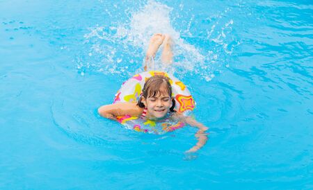 The child swims in the pool in the summer. Selective focus.