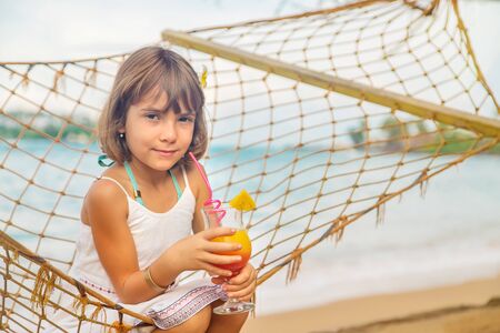 Child girl drinks cocktail on the beach. Selective focus.の写真素材