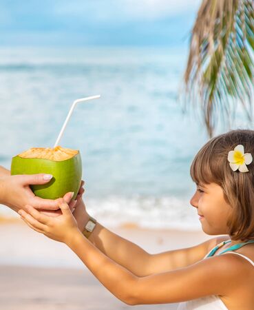 Mother and daughter drink coconut on the beach. Selective focus.の写真素材